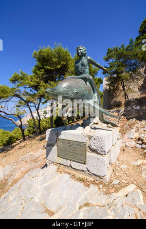 Garçon sur un dauphin de bronze statue, une oeuvre artistique sur sur le film du même nom, tourné ici en 1957, l'île d'Hydra, Grèce Banque D'Images