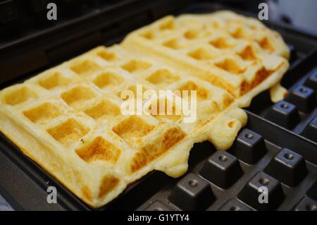 La cuisson des gaufres dans la gaufre-bouilloire Banque D'Images