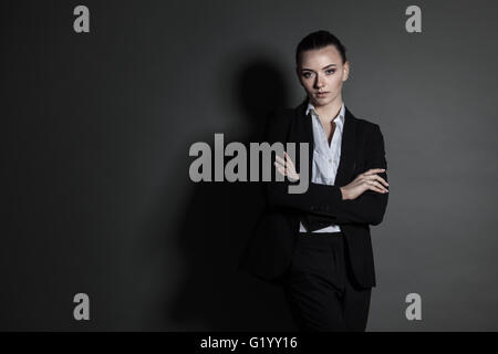 Portrait of young businesswoman en costume noir sur fond sombre Banque D'Images