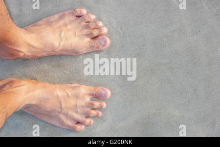 Men's feet on the beach. Banque D'Images