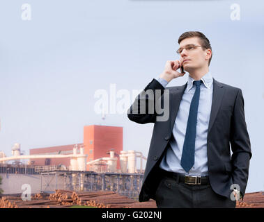 Beau jeune homme d'affaires sur l'arrière-plan d'un bâtiment industriel Banque D'Images