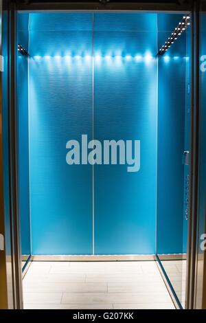 Un ascenseur moderne bleu vide ou ascenseur avec portes métalliques qui sont ouverts dans le bâtiment avec l'éclairage. Banque D'Images