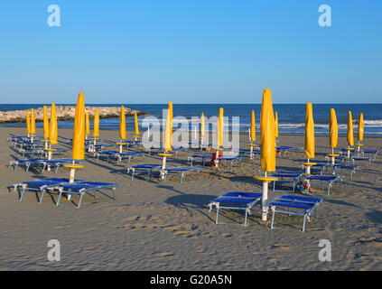 Fermé jaune parasols sur la plage avec chaises longues et transats Banque D'Images