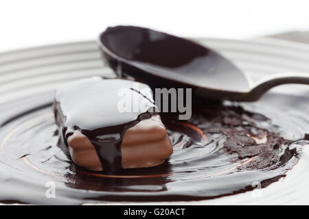 Gros plan du cookie recouvert de chocolat fondu noir avec éclairage arrière Banque D'Images