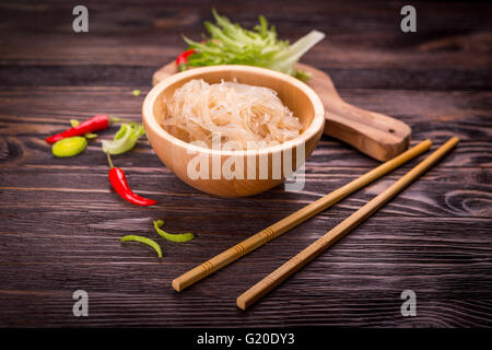 Ingrédients de la cuisine asiatique - riz nouilles, poireau, laitue, piment rouge foncé sur un fond de bois Banque D'Images