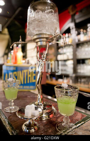 Nuremberg, Allemagne. 19 mai, 2016. Une absinthe fontaine vu sur le comptoir à la barre de la 'Casablanca' cinéma à Nuremberg, Allemagne, 19 mai 2016. Les cuillères en métal perforé avec crochets sont conçus pour s'adapter sur les verres à absinthe afin que le sucre en cubes, qui sont placés sur le haut de la cuillère, se dissout par l'eau de la glace dégoulinant fontaine absinthe. Tujon-contenant l'absinthe était interdit en Allemagne et la plupart de l'Europe depuis des décennies. Aujourd'hui, la boisson spiritueuse, faite à partir de la plante d'absinthe, est devenu un établissement emblématique boisson culte. Photo : DANIEL KARMANN/dpa/Alamy Live News Banque D'Images