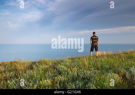 L'homme sur le bord. Falaise de montagne et mer. Scène conceptuelle. Banque D'Images