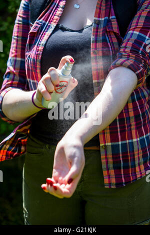 L'insectifuge, jeune femme utilise un spray anti-moustiques, avant une randonnée, en le vaporisant sur le la peau, Banque D'Images