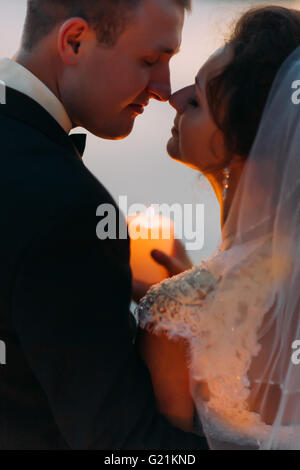 Heureux mariés à moment avant de baiser avec une bougie, close-up Banque D'Images