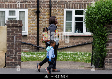 Mère de deux enfants marchant à travers votre conseil à Londres, Angleterre Royaume-Uni UK Banque D'Images