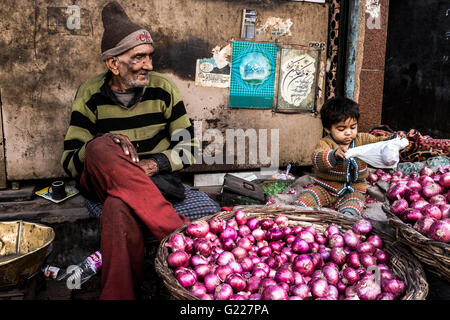 L'homme de vendre les oignons à côté d'un petit enfant, Delhi, Inde Banque D'Images