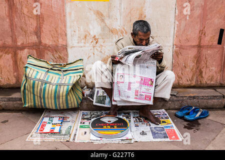 La lecture de l'homme tout en papier qu'il attend d'être clients de se peser, Delhi, Inde Banque D'Images