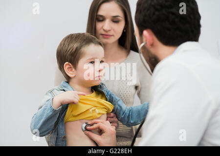 Médecin examinant un garçon de l'école avec sa mère au bureau de l'hôpital Banque D'Images