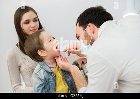 Petit garçon ayant sa gorge examiné par un professionnel de la santé Banque D'Images