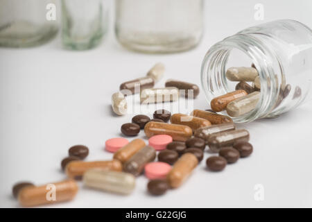 Comprimés et gélules dispersées sur un fond blanc. Banque D'Images