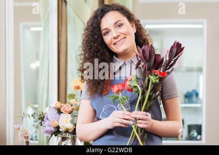 Magnifique Portrait de femme bouclés debout dans le magasin de fleurs fleuriste Banque D'Images