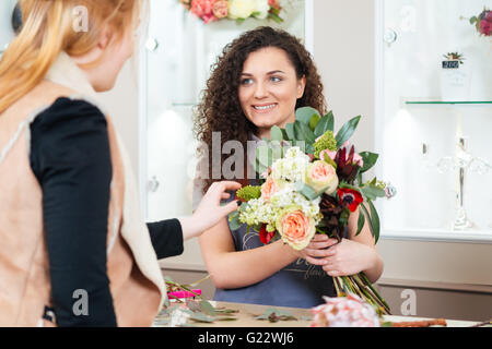 Smiling attractive young woman showing fleuriste bouquet de fleurs au client Banque D'Images
