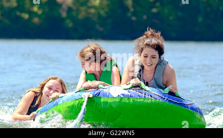 Trois tubes de filles derrière un bateau, un holding sur le l'eau. Banque D'Images