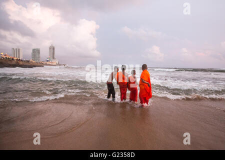 Colombo, Sri Lanka, 23 mai, 2016. Les jeunes moines novices et d'autres jouent dans la mer au coucher du soleil à Galle Face Green. C'est un jour férié, et la troisième Journée du Vesak, qui commémore la naissance de Bouddha, son illumination et atteindre son décès sur le jour de pleine lune de mai qui est tombée cette année le 21 mai. Colombo, Sri Lanka. Banque D'Images