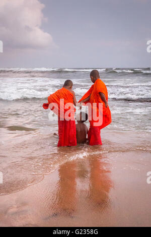 Colombo, Sri Lanka, 23 mai, 2016. Les jeunes moines novices et d'autres jouent dans la mer au coucher du soleil à Galle Face Green. C'est un jour férié, et la troisième Journée du Vesak, qui commémore la naissance de Bouddha, son illumination et atteindre son décès sur le jour de pleine lune de mai qui est tombée cette année le 21 mai. Colombo, Sri Lanka. Banque D'Images
