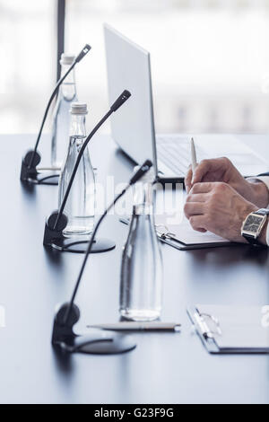 Des micros sur le tableau dans la salle de conférence et homme d'affaires, mains Banque D'Images