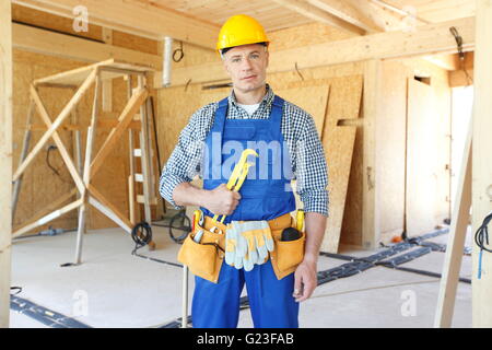 Workman à l'aide d'une clé à l'intérieur de maison en bois en construction Banque D'Images