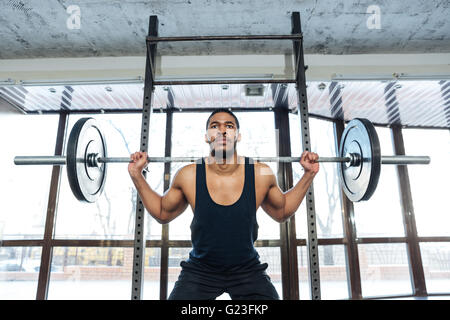 L'haltérophile musclé faisant squats barbell en utilisant l'exercice dans la salle de sport Banque D'Images