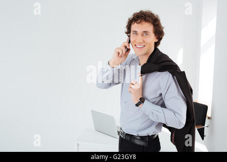 Smiling businessman talking on the phone in office Banque D'Images