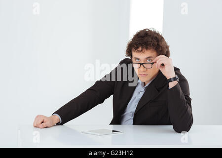 Serious businessman assis à la table et looking at camera Banque D'Images