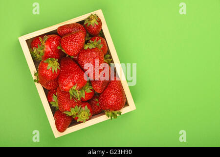 Frais d'été rouge moelleux fraises en plateau en bois fort sur fond de papier vert, vue du dessus Banque D'Images