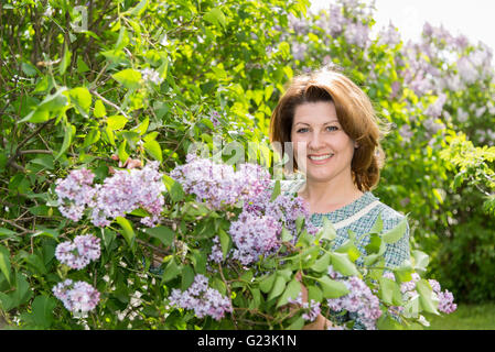 Femme adulte dans la région de Park près de la floraison lilas Banque D'Images