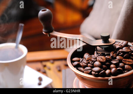 Rectifieuse de café avec des grains de café fumant à l'arrière-plan close up Banque D'Images