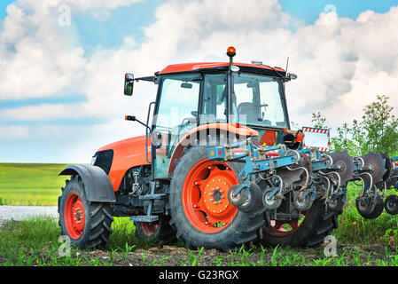 Tracteur rouge moderne sur le domaine agricole. Banque D'Images