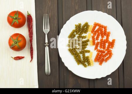 Les pâtes rotini trois couleurs sur une plaque. Pâtes de couleur sur la table de la cuisine. La publicité sur les pâtes. Banque D'Images