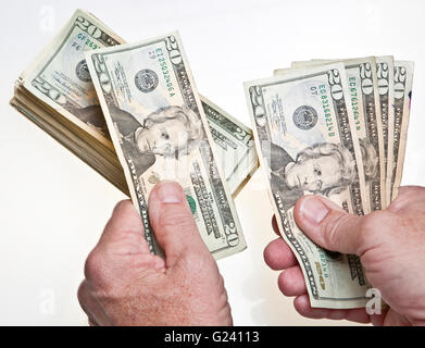 Older Man's hands comptant vingt dollars dans une pile sur fond blanc Banque D'Images