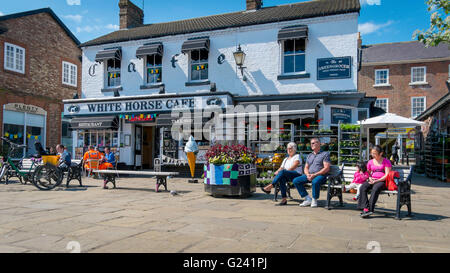 Les gens se détendre avec des glaces à l'extérieur du Cheval Blanc Café à Thirsk Market Place au centre ville, sur une journée de printemps chaud Banque D'Images