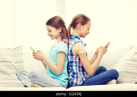 Heureux les filles avec les smartphones sitting on sofa Banque D'Images