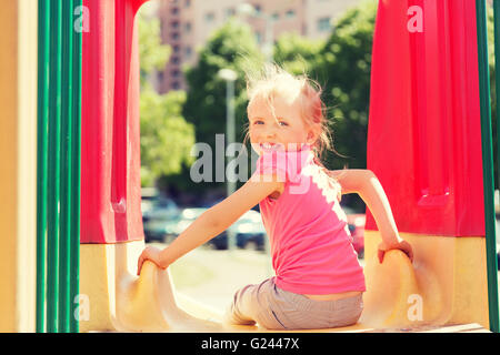 Happy little girl sur la diapositive à l'aire de jeux pour enfants Banque D'Images