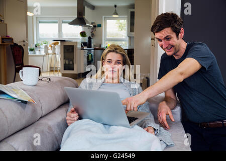 Mari et femme de passer du temps ensemble sur le canapé avec un ordinateur portable, et souriant. plan moyen. Banque D'Images