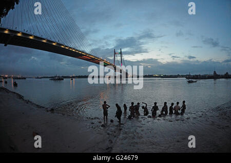 La population locale se baigner dans la rivière Hooghly avec deuxième pont à Hooghly, fond de nuit, Kolkata, West Bengal, India Banque D'Images