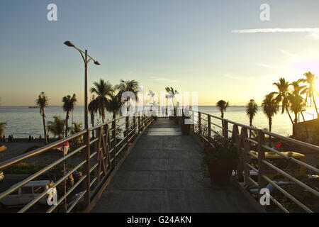 Manille, deux personnes sur passerelle sur Roxas Blvd sur la baie de Manille aux Philippines durant le coucher du soleil, Banque D'Images