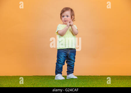 Un mignon bébé fille sur fond orange Banque D'Images