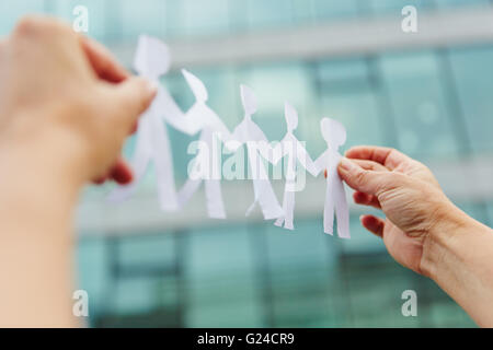 Deux mains tenant une équipe entreprise faits de papier découpés Banque D'Images