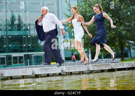 Deux smiling women chasing senior business man sur un pont Banque D'Images
