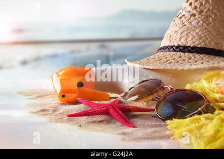 Articles de protection solaire avec des étoiles de mer sur le sable dans une table en verre en terrasse donnant sur plage et soleil. Composition horizontale. Banque D'Images