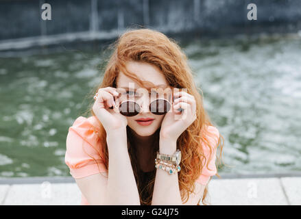 Portrait d'une jeune rousse woman wearing sunglasses Banque D'Images