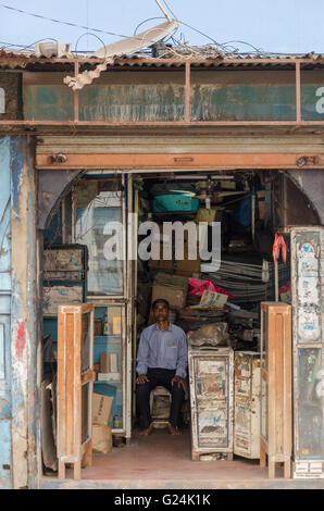 Un vieux shop keeper est assis sur un tabouret à l'intérieur de son magasin sur MG Road, Panjim, Goa, Inde Banque D'Images