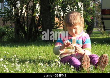 Petite fille aux fleurs Daisy sur une herbe dans le jardin Banque D'Images