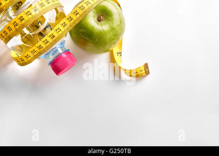 Ruban à mesurer autour d'une bouteille d'eau minérale et d'Apple sur le tableau blanc. Concept de la santé, de l'alimentation et la nutrition. Banque D'Images