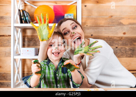 Excité et peu joyeuse mère fils peint avec les mains dans les peintures colorées de s'amuser ensemble Banque D'Images